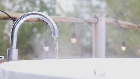 el agua fluye de un grifo al aire libre con el tiempo.