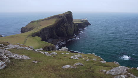 Tracking-shot-of-Neist-Point-lighthouse-with-rocky-cliffs-in-foreground-and-Atlantic-Ocean-in-the-background-on-a-windy-and-cloudy-day-in-Scotland,-Isle-of-Skye