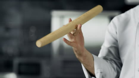 chef playing with roller at workplace. closeup man hands twist roller at kitchen