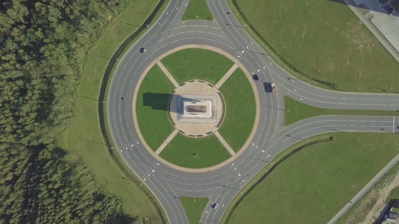 la cámara del dron gira alrededor de un anillo circular de tráfico en una avenida de la ciudad.