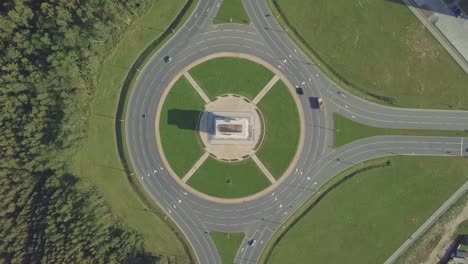 the drone camera rotates around a circular traffic ring on a city avenue.