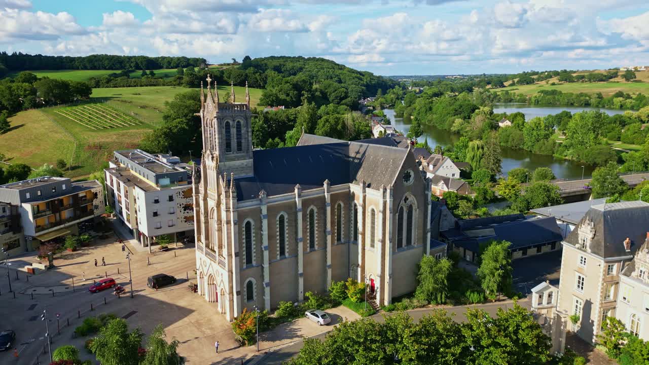 Orbiting drone movement around the historic Saint-Pierre Church of Chenillé-Changé aka Église Saint-Pierre de Chenillé-Changé, Changé, Mayenne, France