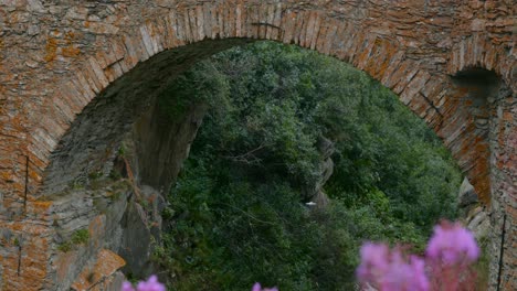 white drone flying under arch of brick bridge