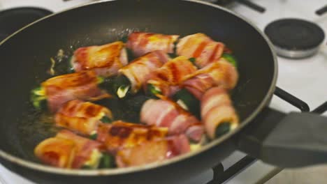 golden color bacon wrapped around a jalapeno with mozzarella stuffing