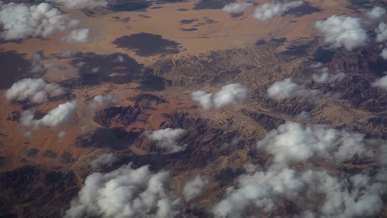 Stunning aerial footage captured by aircraft flying over barren terrain in Jordan. Features rugged desert landscapes, dry valleys, and rocky formations under warm natural light