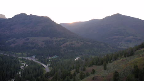 sunrise over a forested mountain valley with a winding road and river