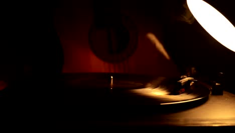 slider shot. disco de vinilo vintage tocando en el reproductor y la guitarra acústica en el fondo con humo de naranja de fuego. concepto de crimen o blues con instalación de automóvil de juguete. enfoque selectivo