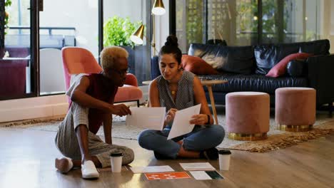 front view of young cool mixed-race business colleagues planning and sitting on floor of modern offi