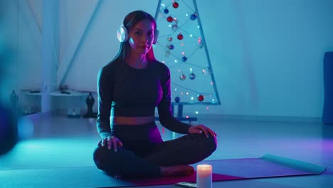 woman meditating on yoga mat near a christmas tree