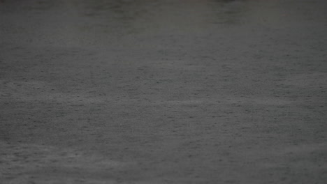 dark water surface with rain falling, creating ripples and reflections, evoking a calm and serene atmosphere in nature