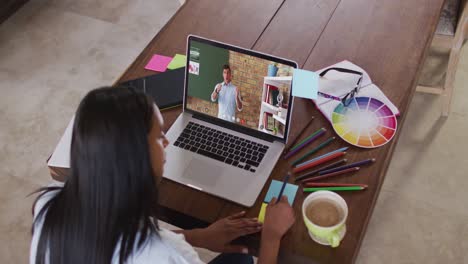 Estudiante-Caucásica-Usando-Una-Computadora-Portátil-En-Una-Videollamada-Con-Un-Maestro,-Tomando-Notas