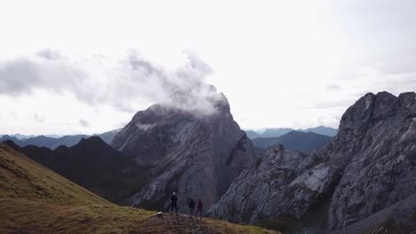 three people are hikeing in alps - drone flight over some people in alps