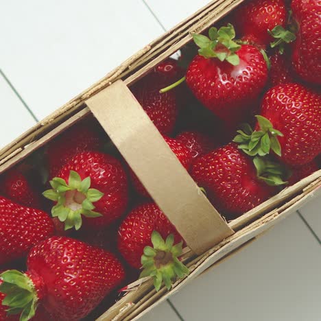 wooden container with fresh red strawberries  placed on white table