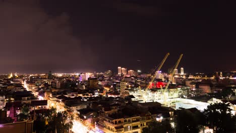 phnom penh cityscape - cranes moving on construction site in foreground