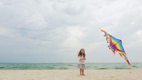 3yo girl playing with a kite on the beach 01