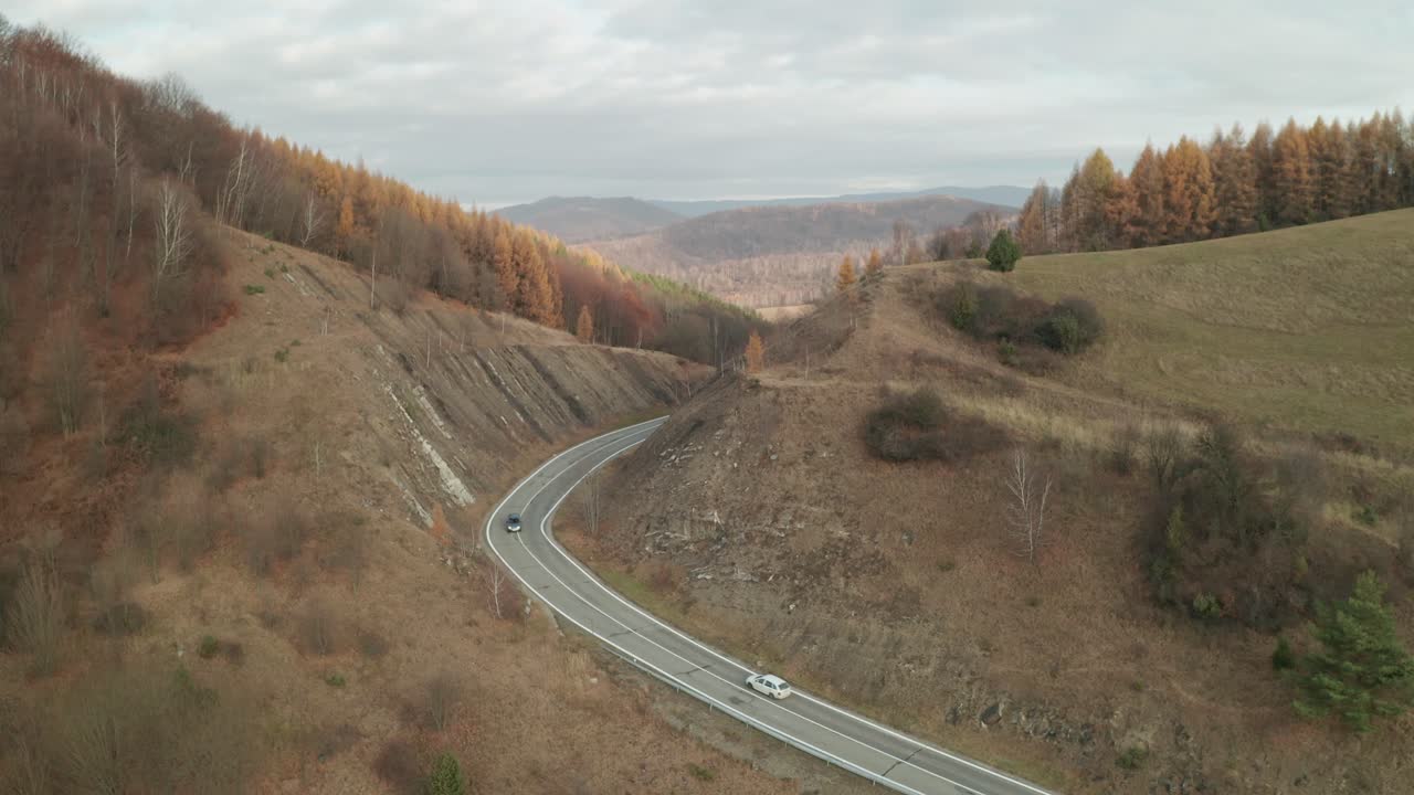 una vista aérea de drones de autos conduciendo en un camino sinuoso que atraviesa un cañón a finales de otoño