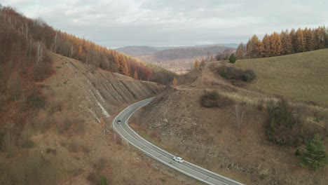 Eine-Luftdrohnenansicht-Von-Autos,-Die-Im-Spätherbst-Auf-Einer-Kurvenreichen-Straße-Durch-Eine-Schlucht-Fahren