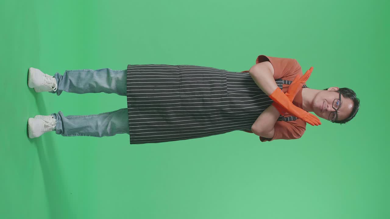녹색 스크린 스튜디오에 서 있는 동안 금지 행동을 보여주는 전면으로 동의하지 않는 아시아 남성 집주인