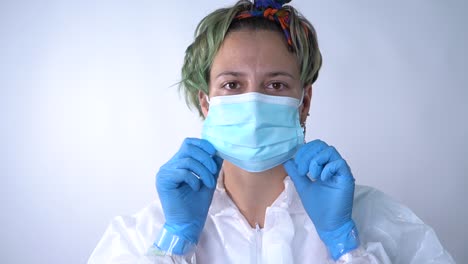 doctor in ppe suit, puts on the mask and indicates to the camera that we should do the same