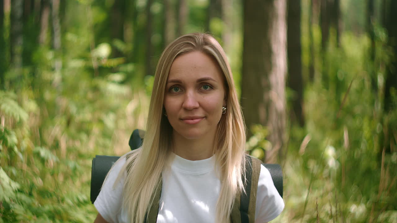 Atmospheric close-up portrait of young beautiful smiling girl in hat with flying hair at forest slow motion