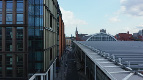 Forwards-fly-above-street-leading-between-modern-building-and-new-part-of-St-Pancras-train-station.-London,-UK