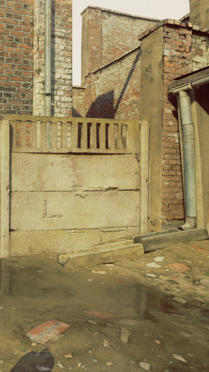 Concrete wall beside brick buildings with water on the ground near an alley