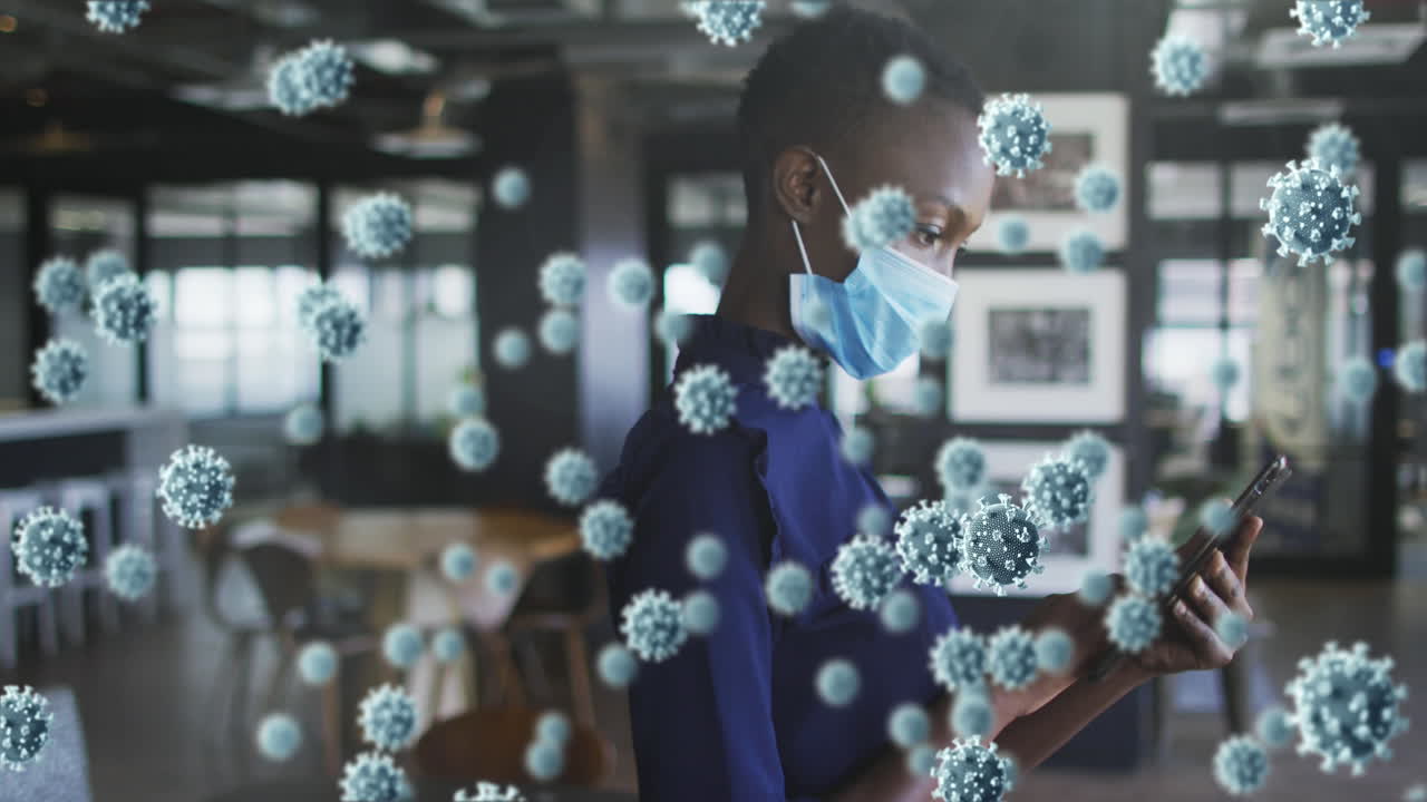 Animation of covid 19 cells floating over woman in face mask using smartphone in office
