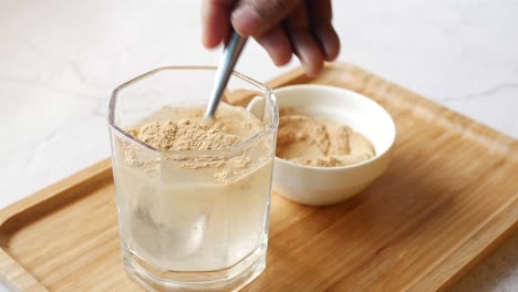 mixing brewers yeast flakes in a glass of water