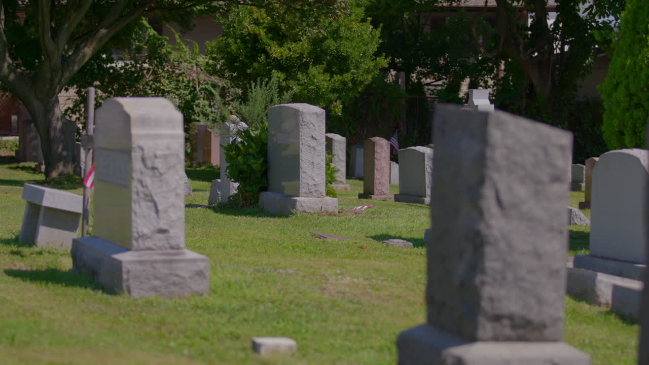 Headstones at Pelham Cemetery, The Bronx. US flag beside a headstone. On a sunny day.