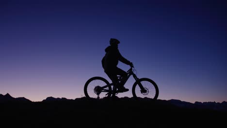 a cyclist is standing on top of a ridge at dawn