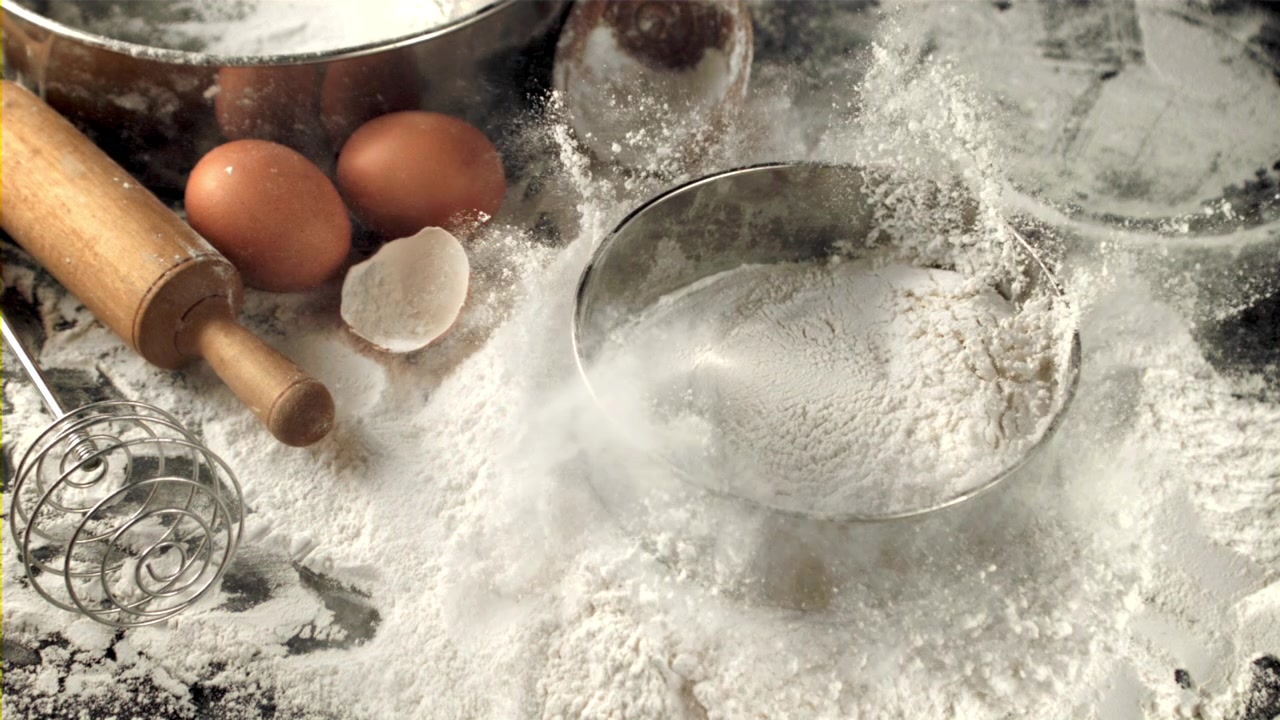 Mel siktes ned i en metallring med bakeingredienser