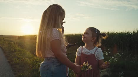 Two-little-caucasian-girls-spending-time-on-village-road-and-picking-wildflowers.