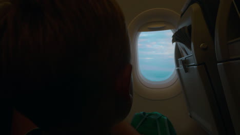 child looking out the illuminator in plane