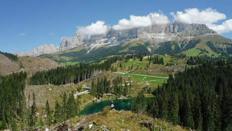 women on top of hill with uprooted pine trees after strong wind in lake carezza - most beautiful lakes in south tyrol, dolomites. circle parallax drone motion