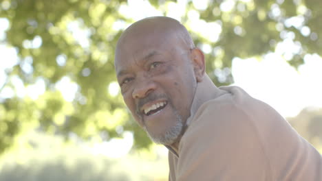 portrait of happy senior biracial man at balcony at home over forest, slow motion