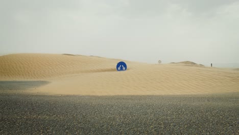 desert road with sand dunes and traffic sign