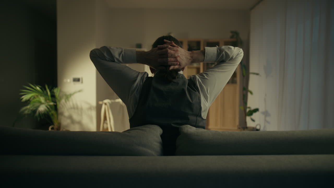 Man Relaxing and Stretching on Sofa in Modern Living Room
