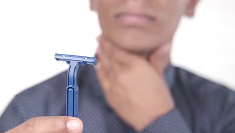 man holding a razor, looking uncomfortable.