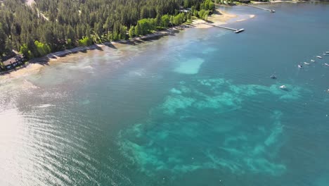 Drone-fly's-above-North-lake-tahoe-with-boats-anchored-in-shallow-water-towards-a-savemart-in-Tahoe-city