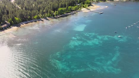 drone fly's above north lake tahoe with boats anchored in shallow water towards a savemart in tahoe city