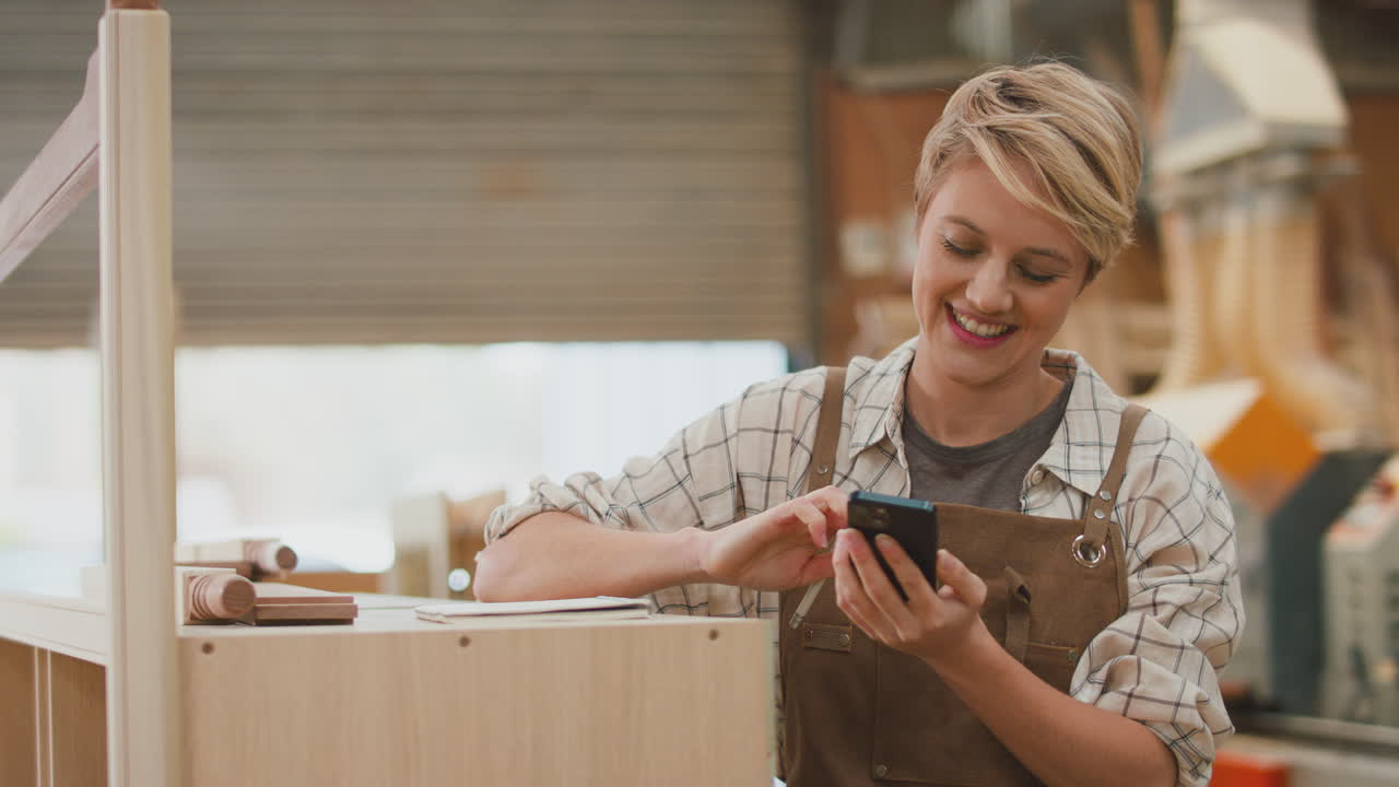 женщина-ученик-плотник, работающая в мебельной мастерской по телефону, делая заметки