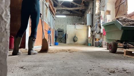 Girl-in-wellington-boots-sweeping-the-stable-floors