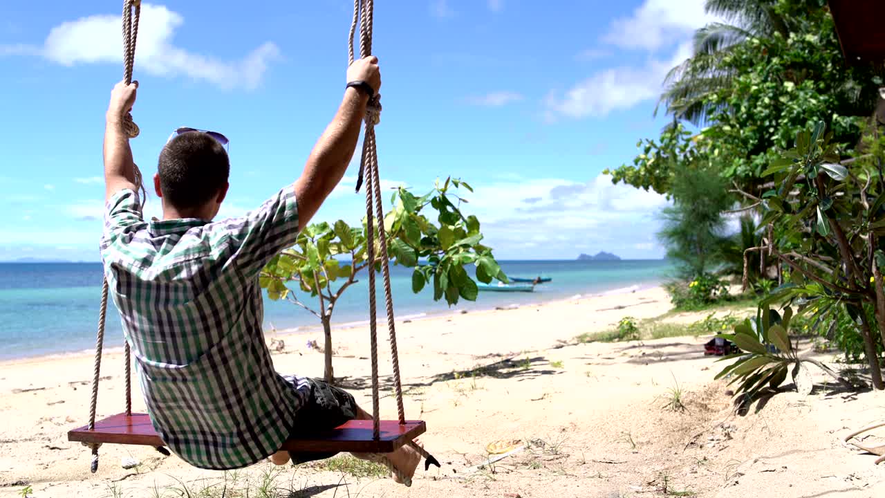 un hombre balanceándose en un columpio junto al mar