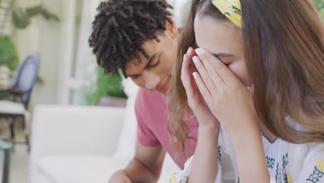 Sad-biracial-couple-spending-time-at-home-together-sitting-on-couch-and-cheering