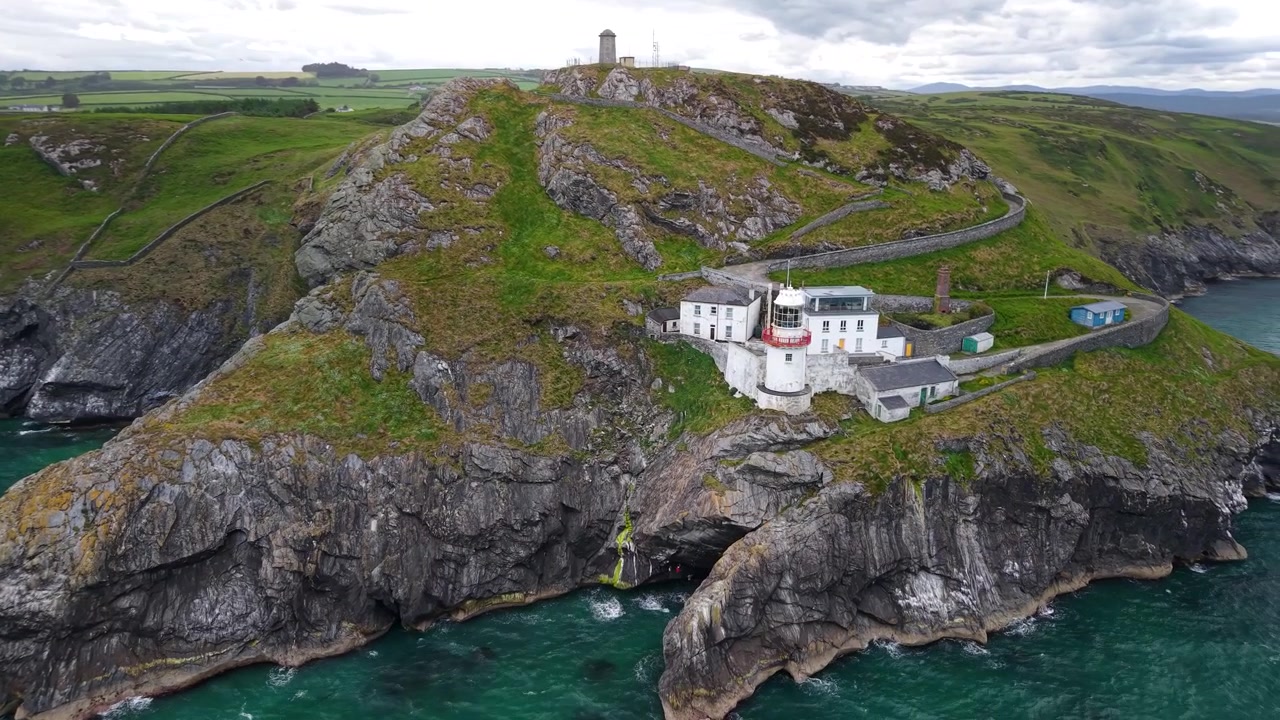 Hermosa vista aérea del Faro de Old Wicklow Head y el escarpado paisaje costero en Wicklow, Irlanda