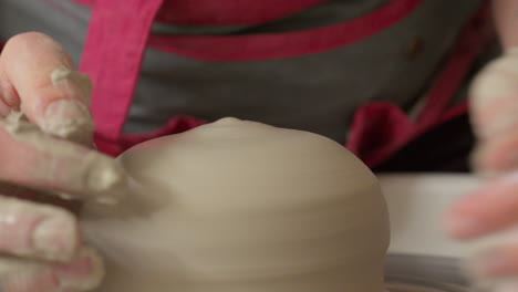 Pottery artist carefully centering a piece of clay on the throwing wheel with both hands