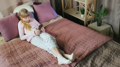 teenage girl uses a smartphone in her bedroom