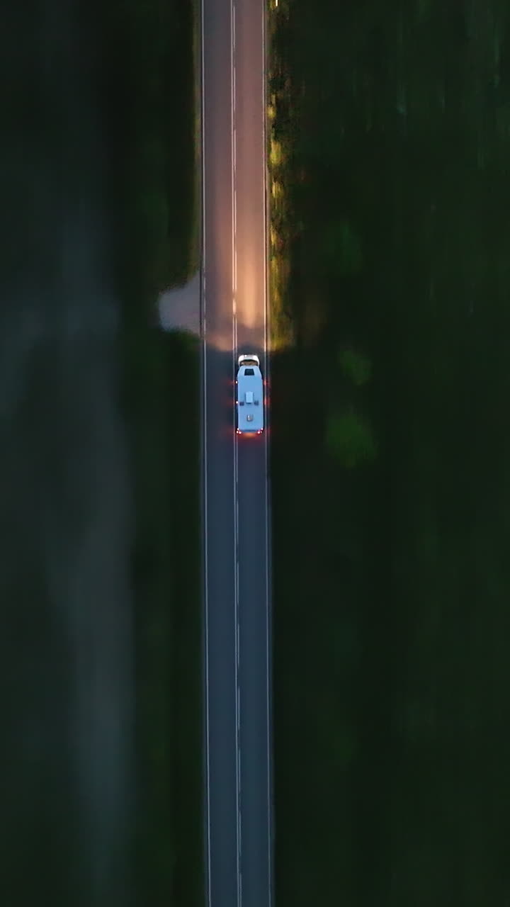 Aerial portrait shpt on top of a RV driving through the countryside, blue hour