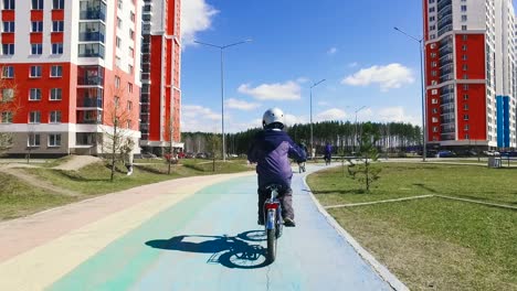 niño montando una bicicleta en un parque de la ciudad