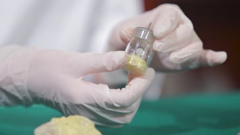 scientist holding a small vial with a yellow substance